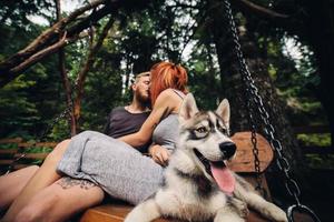 beautiful couple together with dog on a swing photo