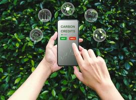 Trader using smartphone to trade carbon credits on application. Net zero emission, Clean technology, Renewable energy concept. photo