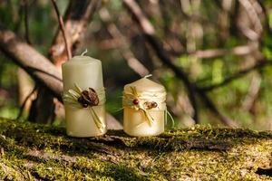 two candles, two candles on an old log in the forest. photo