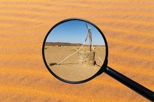 pozo de agua en el desierto del sahara, vista a través de una lupa, fondo de arena foto