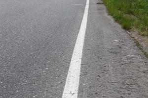 línea continua blanca. señalización vial en una carretera asfaltada. enfoque selectivo foto