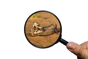 saddle for camel on the sand, view through a magnifying glass on a white background, magnifying glass in hand. photo