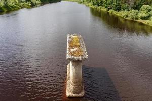 Old bridge support stands in river photo