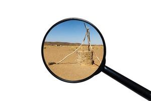 pozo de agua en el desierto del sahara, vista a través de una lupa, fondo blanco foto