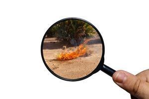 hierba seca quemada en el desierto del sahara, vista a través de una lupa sobre un fondo blanco, lupa en la mano foto