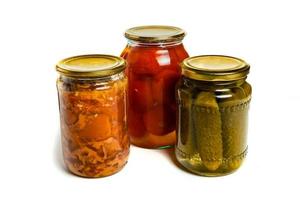 three glass jars on white background, pickled cucumbers, pickled tomatoes and canned meat photo