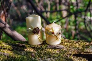 two candles on an old log in the forest photo