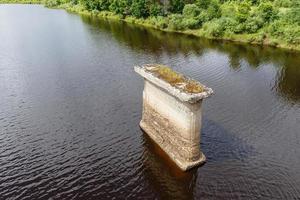 Old bridge support, support of the destroyed bridge stands in the river. photo