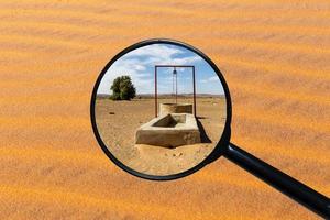 pozo de agua en el desierto del sahara, vista a través de una lupa, fondo de arena foto