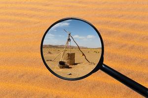 pozo de agua en el desierto del sahara, vista a través de una lupa sobre el fondo de la arena foto