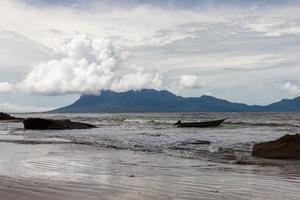 boat moored at the shore against a background of mountains and sky with clouds, Borneo, Malaysia photo