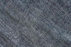 Detailed abstract texture of dark blue denim cloth. Background image of old used denim trousers fabric photo