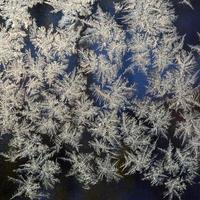 Snowflakes frost rime macro on window glass pane photo