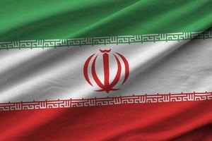 Iran flag with big folds waving close up under the studio light indoors. The official symbols and colors in banner photo