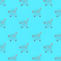 Shopping addiction, shopping lover or shopaholic concept. Many small empty shopping carts perform a pattern on a pastel colored paper background. Flat lay composition, top view photo