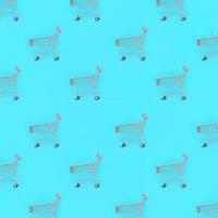 Shopping addiction, shopping lover or shopaholic concept. Many small empty shopping carts perform a pattern on a pastel colored paper background. Flat lay composition, top view photo