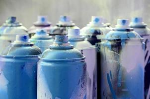 A lot of dirty and used aerosol cans of bright blue paint. Macro photograph with shallow depth of field. Selective focus on the spray nozzle photo