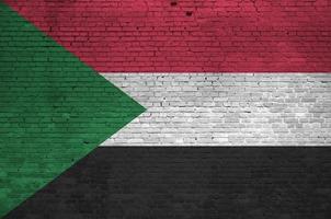 bandera de sudán representada en colores de pintura en la pared de ladrillo antiguo. banner texturizado sobre fondo de mampostería de pared de ladrillo grande foto