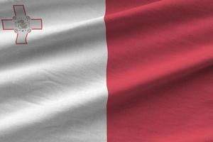 Malta flag with big folds waving close up under the studio light indoors. The official symbols and colors in banner photo