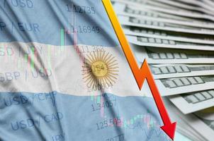 Argentina flag and chart falling US dollar position with a fan of dollar bills photo