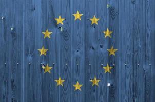 European union flag depicted in bright paint colors on old wooden wall. Textured banner on rough background photo