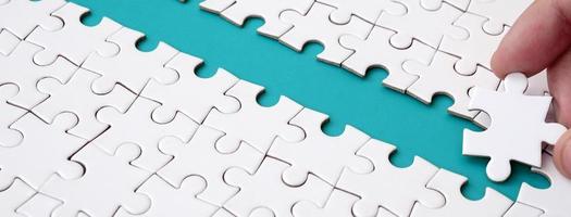 The human hand paves the way to the surface of the jigsaw puzzle, forming a blue space. The concept of overcoming the difficulties on the way to success photo