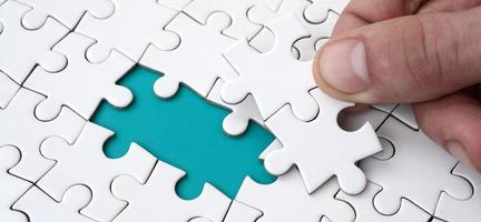 The human hand fills the last missing elements of the surface from the jigsaw puzzle. The concept of the completion of the initiated cases photo