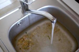 Stainless steel sink plug hole close up full of water and particles of food photo