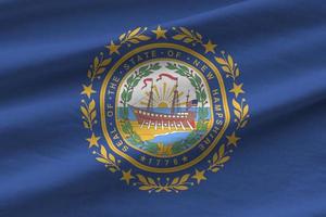 New Hampshire US state flag with big folds waving close up under the studio light indoors. The official symbols and colors in banner photo