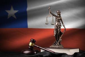 bandera de chile con estatua de la dama de la justicia, constitución y martillo de juez sobre cortinas negras. concepto de juicio y culpa foto