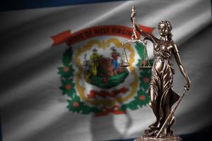 bandera del estado de virginia occidental con la estatua de la dama de la justicia y escalas judiciales en una habitación oscura. concepto de juicio y castigo foto