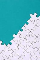 Fragment of a folded white jigsaw puzzle on the background of a blue plastic surface. Texture photo with copy space for text