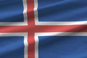 Iceland flag with big folds waving close up under the studio light indoors. The official symbols and colors in banner photo