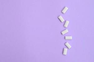 A few chewing gums lie on texture background of fashion pastel violet color paper in minimal concept photo