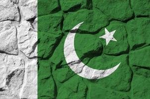 Pakistan flag depicted in paint colors on old stone wall closeup. Textured banner on rock wall background photo