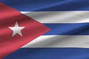 Cuba flag with big folds waving close up under the studio light indoors. The official symbols and colors in banner photo