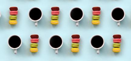 A pattern of many colorful dessert cake macaroon and coffee cups on trendy pastel blue background top view. Flat lay composition photo