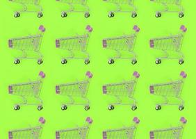 Shopping addiction, shopping lover or shopaholic concept. Many small empty shopping carts perform a pattern on a pastel colored paper background. Flat lay composition, top view photo