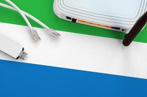 Sierra Leone flag depicted on table with internet rj45 cable, wireless usb wifi adapter and router. Internet connection concept photo