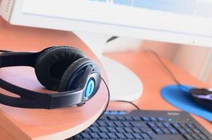 Big black headphones lie on the wooden desktop of the sound designer photo