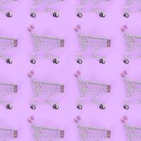 Shopping addiction, shopping lover or shopaholic concept. Many small empty shopping carts perform a pattern on a pastel colored paper background. Flat lay composition, top view photo