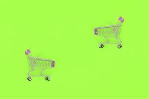 Shopping addiction, shopping lover or shopaholic concept. Small empty shopping cart lies on a pastel colored paper background. Flat lay minimal composition, top view photo