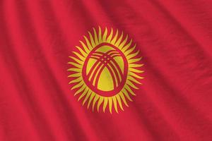 Kyrgyzstan flag with big folds waving close up under the studio light indoors. The official symbols and colors in banner photo