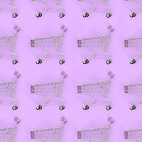 Shopping addiction, shopping lover or shopaholic concept. Many small empty shopping carts perform a pattern on a pastel colored paper background. Flat lay composition, top view photo