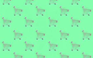 Shopping addiction, shopping lover or shopaholic concept. Many small empty shopping carts perform a pattern on a pastel colored paper background. Flat lay composition, top view photo