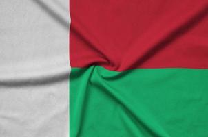 Madagascar flag  is depicted on a sports cloth fabric with many folds. Sport team banner photo