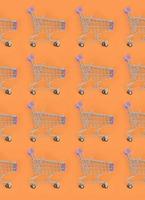 Shopping addiction, shopping lover or shopaholic concept. Many small empty shopping carts perform a pattern on a pastel colored paper background. Flat lay composition, top view photo