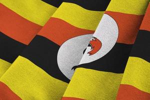 Uganda flag with big folds waving close up under the studio light indoors. The official symbols and colors in banner photo