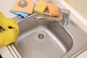 Workers hands in gloves next to a perfectly clean kitchen sink photo