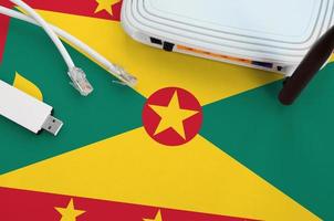 Grenada flag depicted on table with internet rj45 cable, wireless usb wifi adapter and router. Internet connection concept photo